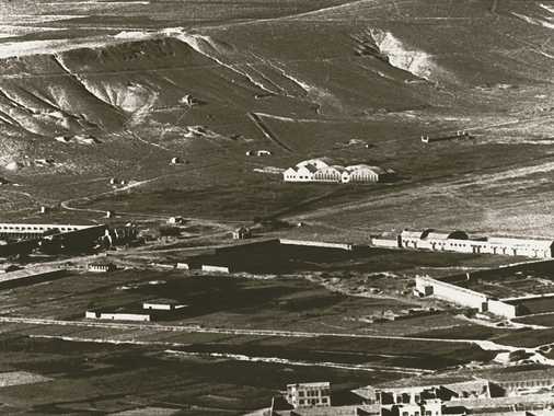 Der erste Flugplatz von Kabul auf der Ebene von Sherpur, südlich der Anhöhe tapa-ye bimaruh. In Bildmitte die Hangars. Von hier aus erfolgte im Winter 1928/29 durch eine englische Luftbrücke die Evakuierung der Europäer von Kabul nach Peshawar. 1937 führte die Lufthansa regelmässige Flüge von und nach Deutschland ein. Dieser Flugplatz blieb bis 1963 in Betrieb.