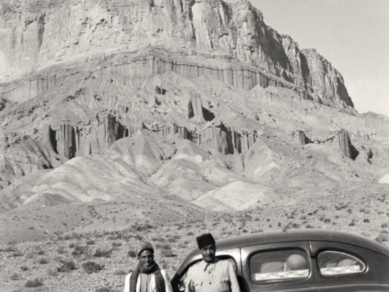 |RS 104|
Zwei Männer vor einer schwarzen Limousine. Im Hintergrund die Steilwand.