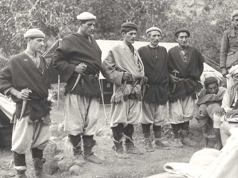Eine Gruppe von fünf Männern in typischer Nuristani-Kleidung der Siah-Posh zu Besuch im Lager der Expedition. Alle fünf tragen den Nuristani-Dolch am Gürtel. Drei Männer tragen einen silbernen Ohrring als Zeichen ihrer sozialen Stellung als dshasht (Häuptling).